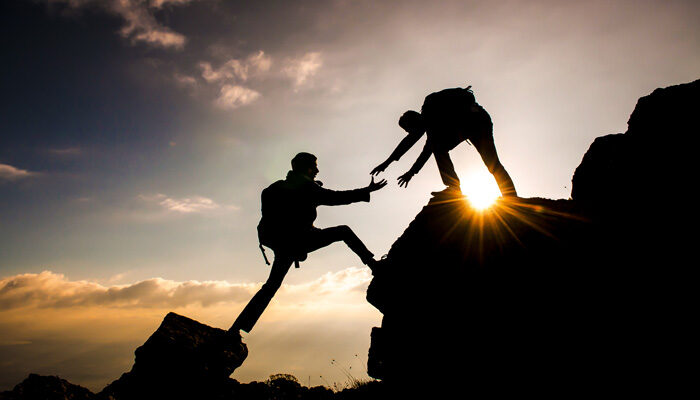 Ein hilfsbereiter Kletterer reicht einem anderen seine Hände